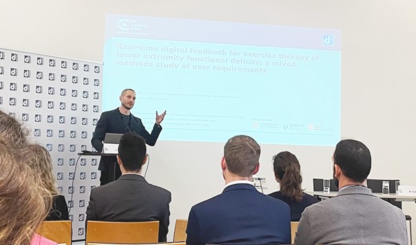 Lukas Maul bei der Präsentation der ersten Ergebnisse des Projektes "Smarte echtzeit-feedback-unterstütze Trainingstherapie (SETT)" auf der dHealth Konferenz 2023.